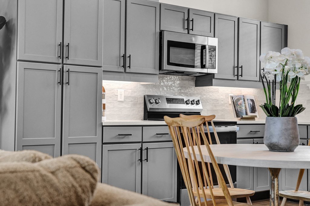 A modern kitchen with custom cabinets, tile backsplash, and stainless steel appliances at West Row Townhomes and at West Row Townhomes at West Row Lofts and Townhomes in Birmingham, AL